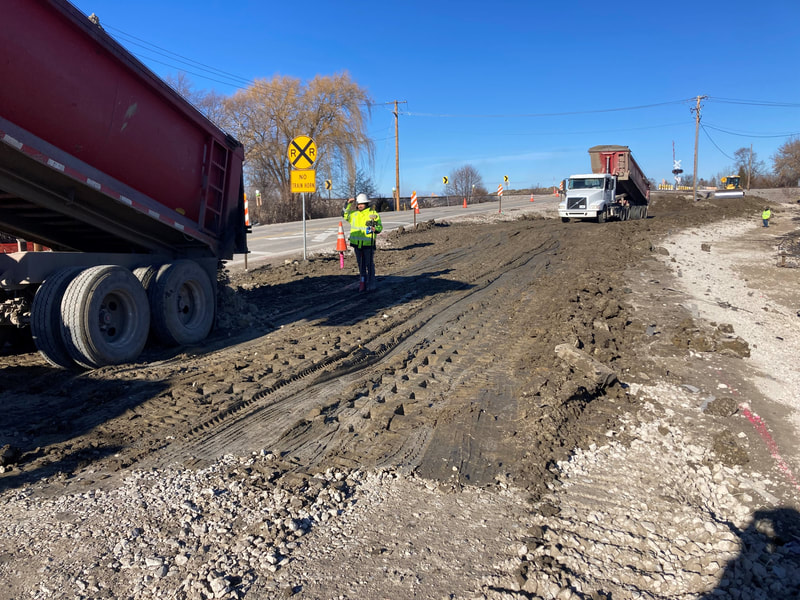 Dump trucks delivering embankment material for the east side of the roadway